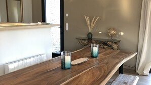 A modern dining area with a long wooden table, benches, and decorative items. - Charming villa with pool in Bonifacio (Bonifacio)