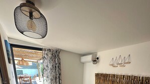 A bedroom with a bed, a hanging light fixture, a wall-mounted air conditioner, and a view of an outdoor patio area. - Charming villa with pool in Bonifacio (Bonifacio)