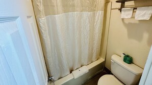A bathroom with a shower curtain, a toilet, and a towel rack. - Economy Inn (Houma)