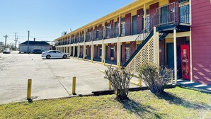 A motel with multiple floors, outdoor parking, and a Coca-Cola advertisement. - Economy Inn (Houma)