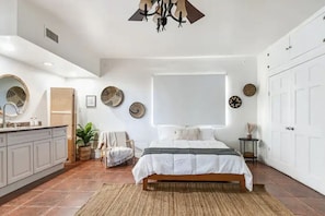 Een slaapkamer met een bed, nachtkastjes, een kaptafel, een raam en een plafondventilator.