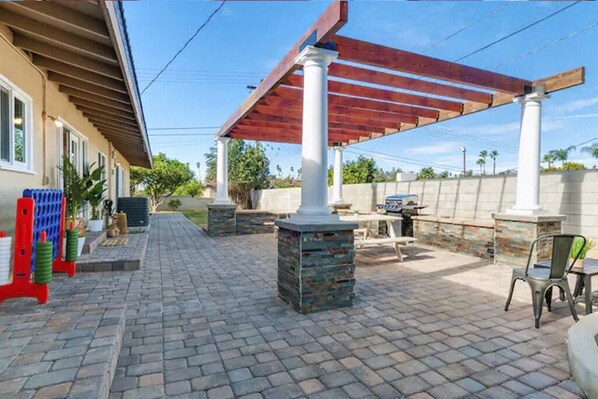 Un espace extérieur aménagé en terrasse, avec une pergola, des piliers en pierre et un sol en briques.
