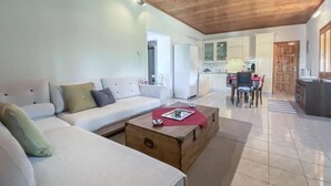 Un salon avec un canapé, une table basse en bois et une cuisine à l’arrière-plan.