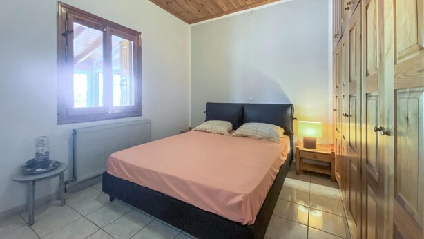 Une chambre à coucher avec un lit, une table de chevet, une lampe, une fenêtre et un radiateur.