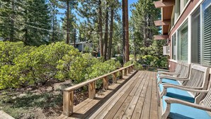 A wooden deck with benches, surrounded by dense greenery and tall trees. - Koyukon Cozy Cabin 3BR,2BA-10 Min. to Ski (South Lake Tahoe)