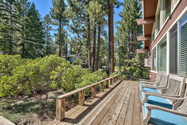 A wooden deck with benches, surrounded by dense greenery and tall trees. - Koyukon Cozy Cabin 3BR,2BA-10 Min. to Ski (South Lake Tahoe)