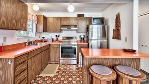 A modern kitchen with wooden cabinets, stainless steel appliances, and a central island with stools. - Koyukon Cozy Cabin 3BR,2BA-10 Min. to Ski (South Lake Tahoe)