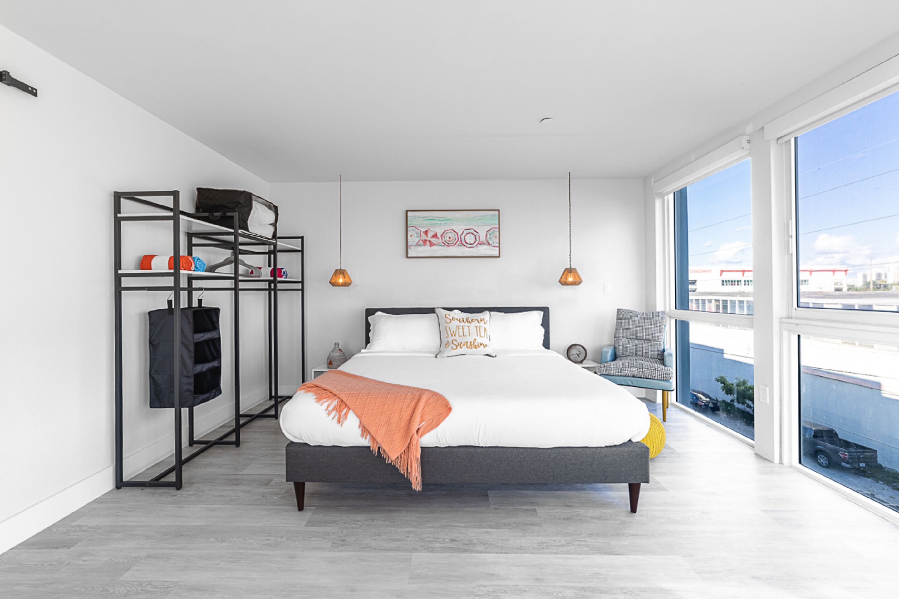 Un dormitorio moderno con una cama grande, un armario, una silla y un balcón con vistas.