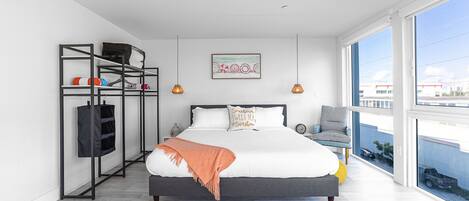 Un dormitorio moderno con una cama grande, un armario, una silla y un balcón con vistas.