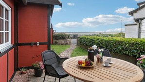 Eine Terrasse mit einem runden Holztisch, Stühlen und einer Obstschale.