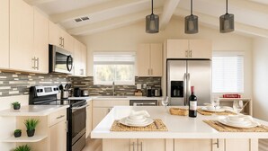 Una cocina moderna con una isla central, electrodomésticos de acero inoxidable e iluminación colgante.