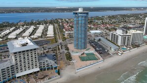 A coastal cityscape with a prominent blue and white tower, a beachfront, and surrounding residential and commercial buildings.