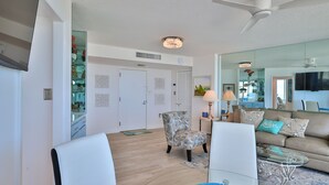 A modern living room with a sofa, armchairs, a coffee table, and a dining area with a glass table.