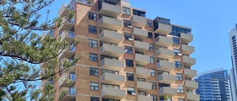 Um edifício residencial com vários andares, varandas, garagem e uma loja à vista.