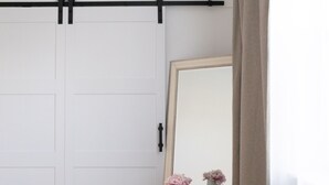 A room with a sliding door, a small round table with a vase of flowers, and a mirror on the wall. - Centrally Located (Eugene)