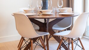 A dining table set with white chairs, a vase of white flowers, and wine glasses. - Centrally Located (Eugene)