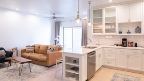 A modern kitchen with white cabinets, a built-in dishwasher, and a small island with a sink. - Centrally Located (Eugene)