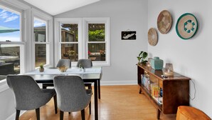 A dining area with a table and chairs, a bookshelf, and decorative wall hangings.