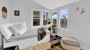 A cozy room with a white sofa, a patterned rug, and a view of a Ferris wheel through large windows.