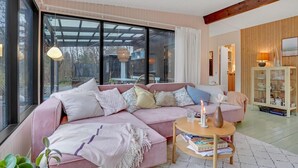 A modern living room with a pink sofa, a wooden coffee table, and a glass cabinet. - Gorgeous home in Strøby with kitchen (Strøby)