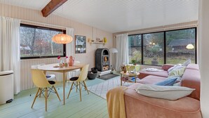 A cozy living room with a fireplace, a dining area, and large windows offering a view of the outdoors. - Gorgeous home in Strøby with kitchen (Strøby)