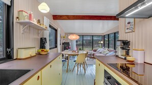 A modern kitchen with a central island, a dining area with a sofa, and a coffee machine. - Gorgeous home in Strøby with kitchen (Strøby)