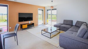 A modern living room with a large flat-screen TV, a grey sofa, a coffee table, and a glass door leading to an outdoor area. - Awesome home in Cléon d'Andran (Cléon d'Andran)