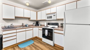 A modern kitchen with white cabinets, a microwave, stove, and a refrigerator. - Downtown Apartment Perfect for Short & Extended Stays (Sioux Falls)