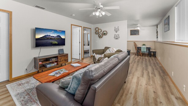 A modern living room with a leather sofa, wooden coffee table, and a mounted TV. - Downtown Apartment Perfect for Short & Extended Stays (Sioux Falls)
