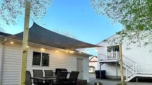 A patio area with a dining table and chairs, a covered seating area, and a staircase leading to a second floor. - Downtown Apartment Perfect for Short & Extended Stays (Sioux Falls)