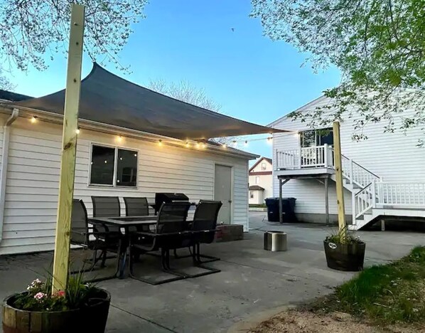 A patio area with a dining table and chairs, a covered seating area, and a staircase leading to a second floor. - Downtown Apartment Perfect for Short & Extended Stays (Sioux Falls)