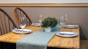 A dining table set with plates, cutlery, and glasses, with a small potted plant in the center. - Downtown Apartment Perfect for Short & Extended Stays (Sioux Falls)