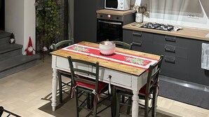 Et moderne køkken med træloft, spisebord med stole, mikrobølgeovn, gasblus og en stenvæg.