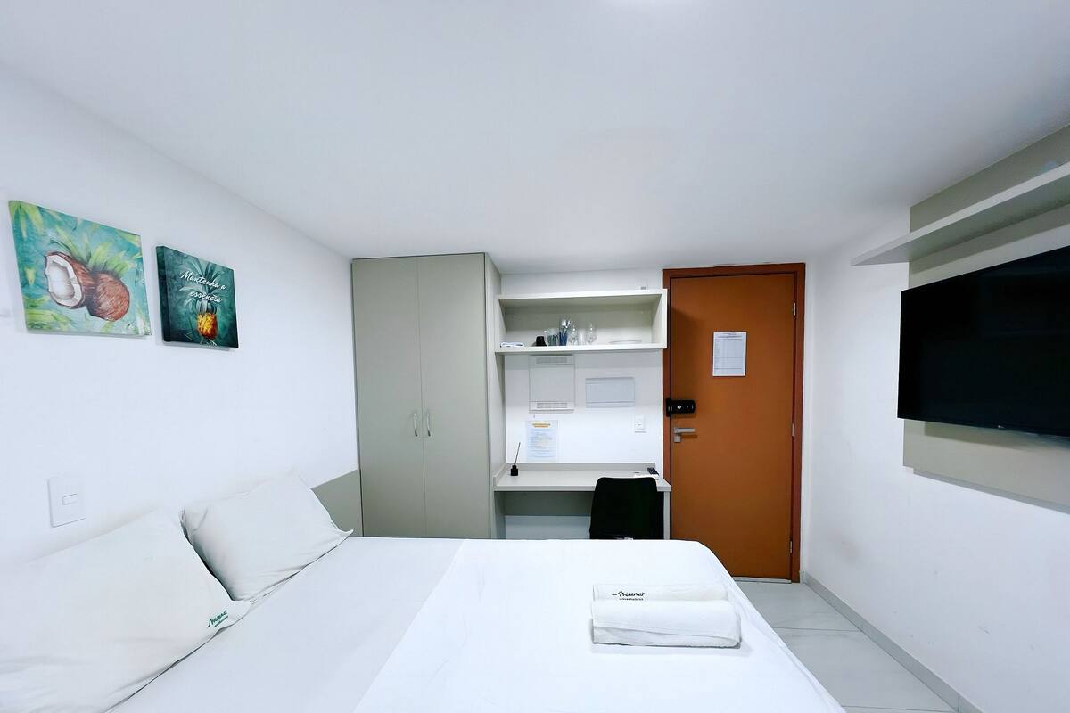 Una camera d'hotel con un letto, una scrivania, un televisore e due opere d'arte appese alle pareti.