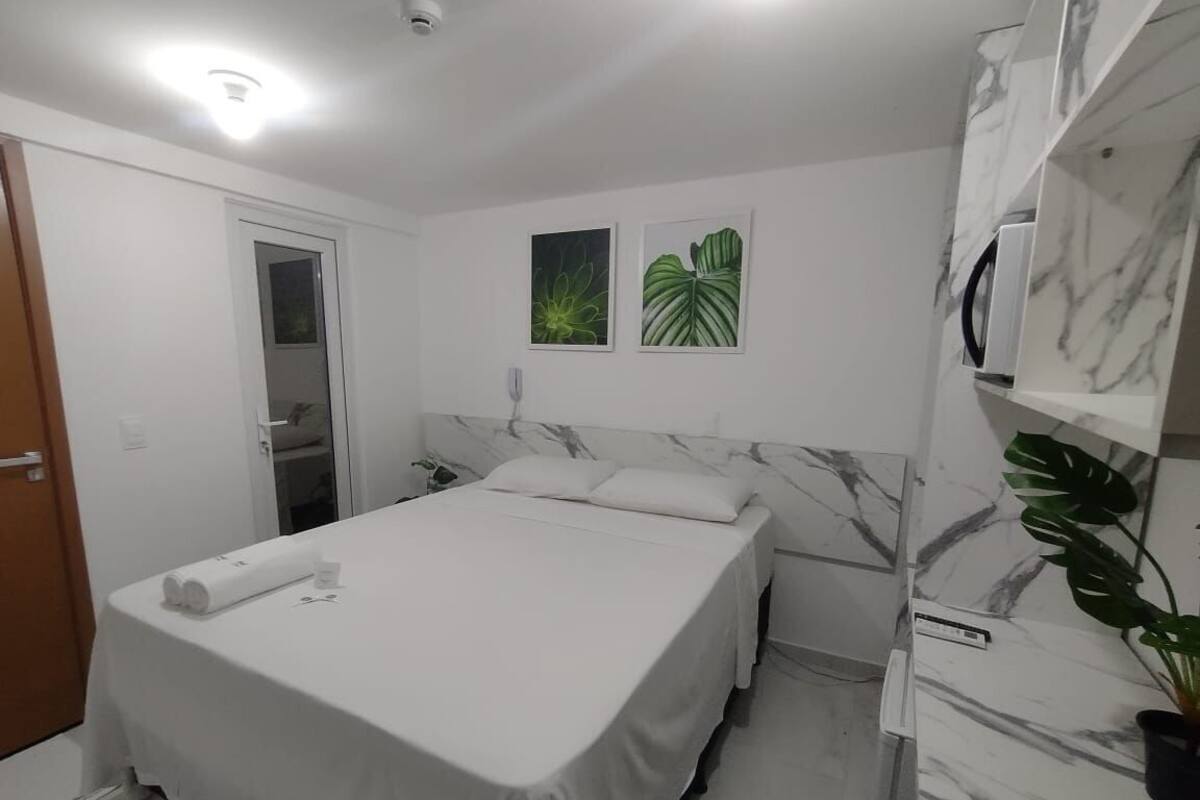 Una camera da letto con un letto, un comodino, uno specchio e una pianta in vaso.