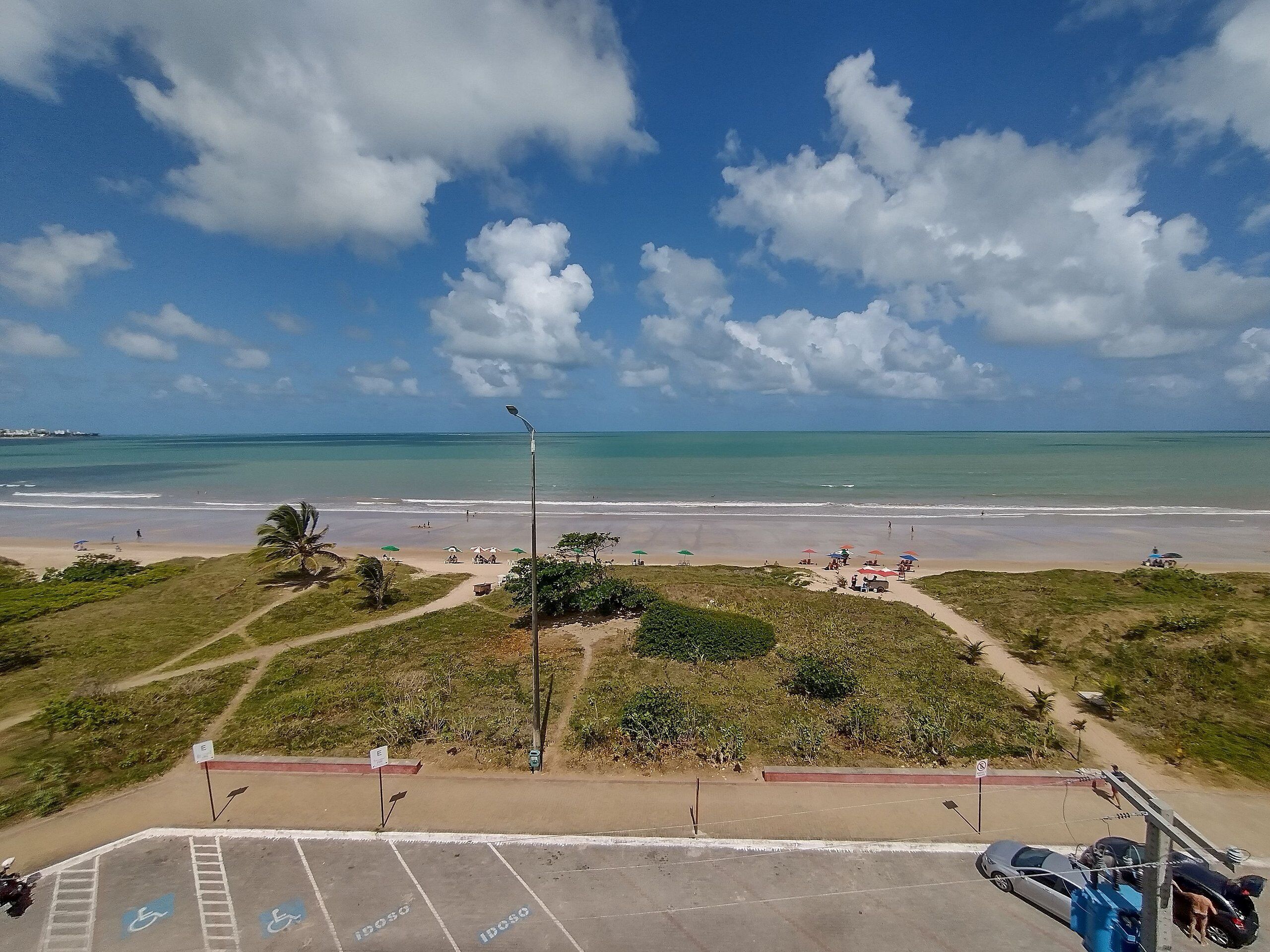 Una playa con un estacionamiento, un camino para peatones y vista al océano.