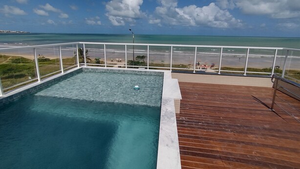 A swimming pool with a wooden deck and a view of the beach and ocean. - Paradise Beach (João Pessoa)