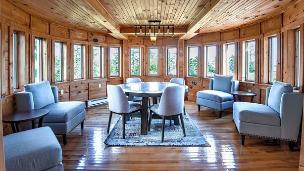 L’intérieur d’un chalet en bois, avec une table ronde, six chaises et un lustre.