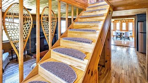Un escalier en bois au design original, menant à un espace repas comprenant une table et des chaises.