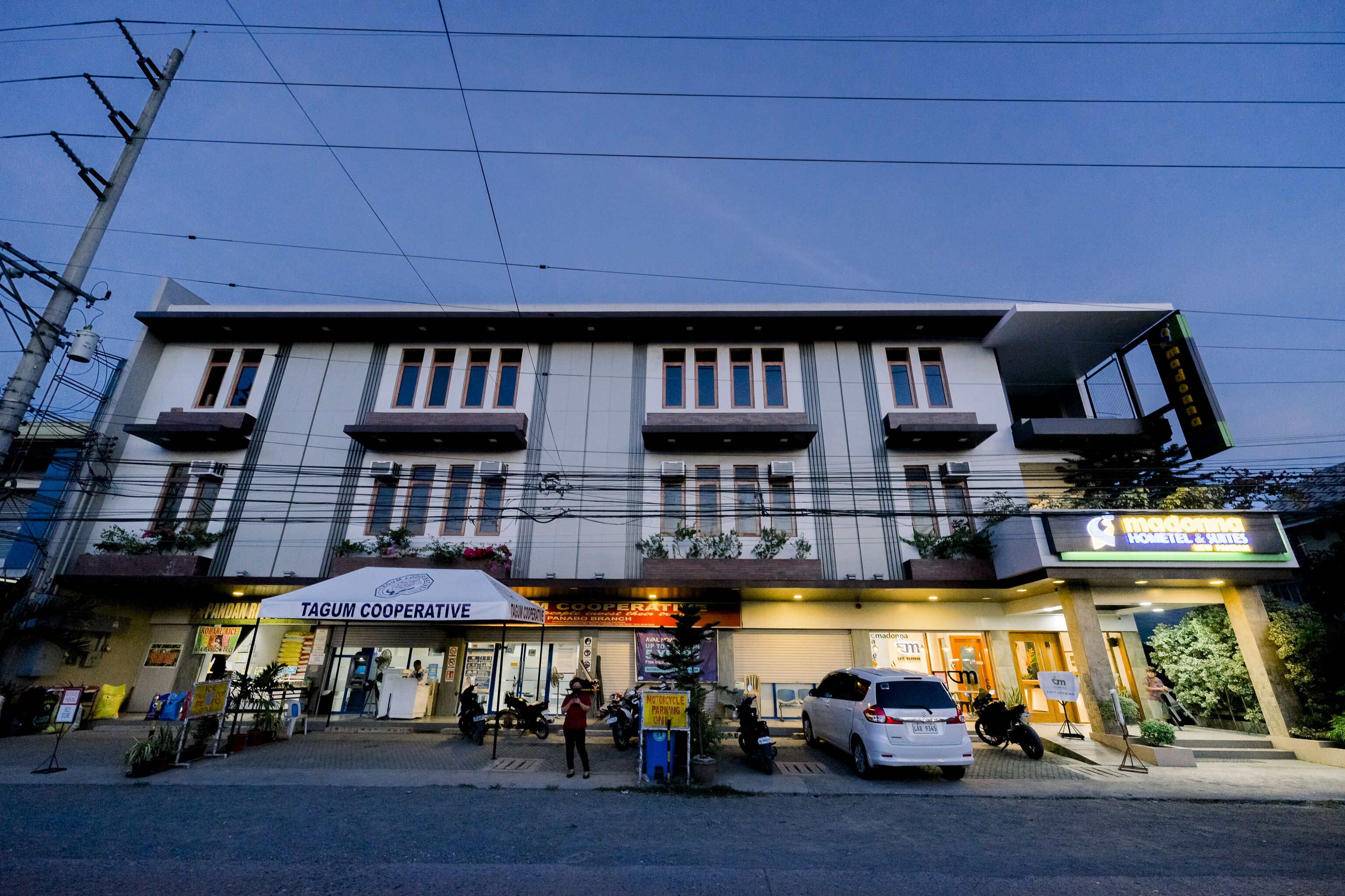 A multi-story building with a Tagum Cooperative sign, a visible entrance, and a parked car.