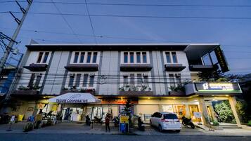 A multi-story building with a Tagum Cooperative sign, a visible entrance, and a parked car.