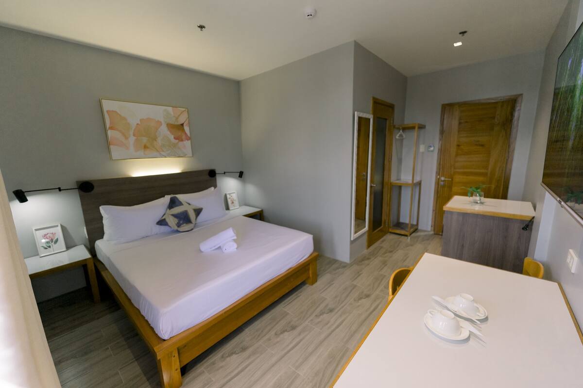 Een moderne hotelkamer met een bed, nachtkastjes, een bureau en een douche.