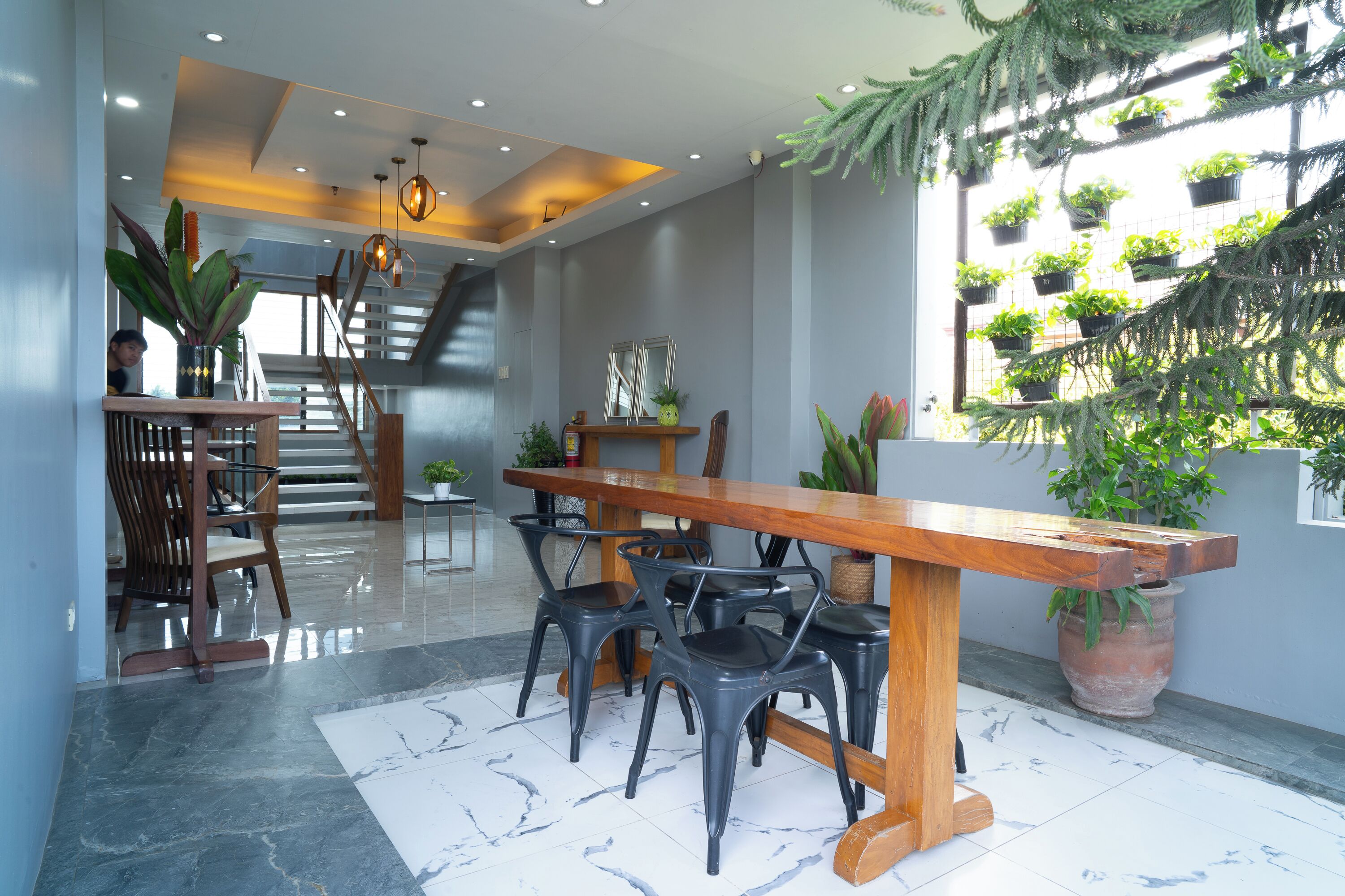 Un intérieur moderne avec une table à manger en bois, des chaises noires et un escalier menant à un niveau supérieur.