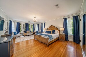 A spacious bedroom with a large bed, a sofa, and a desk.