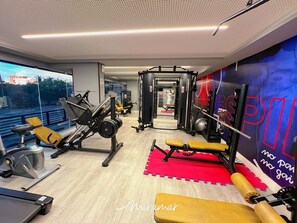 A gym with exercise equipment, a treadmill, and a red mat on the floor. - Urbani Smart Residence (João Pessoa)