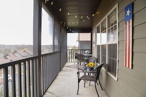 Enjoy the serene neighborhood view from this balcony with a set of wicker chairs and a small table.