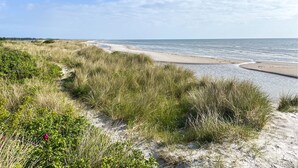 Un paysage côtier avec des dunes de sable, une plage et l’océan.