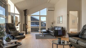 Un salon spacieux doté d’une grande fenêtre, d’une cheminée et d’un coin salon confortable.