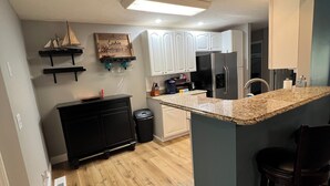 A modern kitchen with white cabinets, a granite countertop, and a built-in island with bar stools. - Incredible KY Lake Waterfront Home with Dock (Gilbertsville)