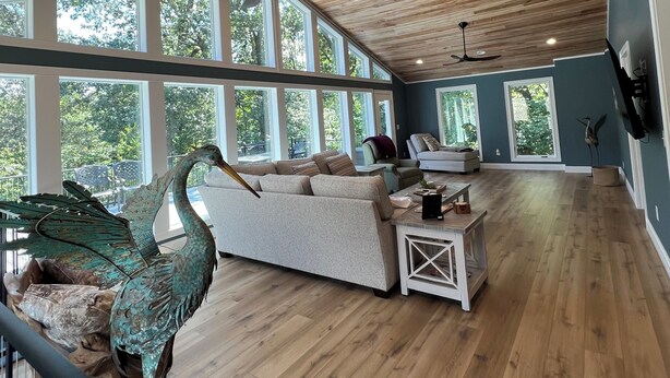 A spacious living area with wooden flooring, a large window, and a ceiling fan. - Incredible KY Lake Waterfront Home with Dock (Gilbertsville)